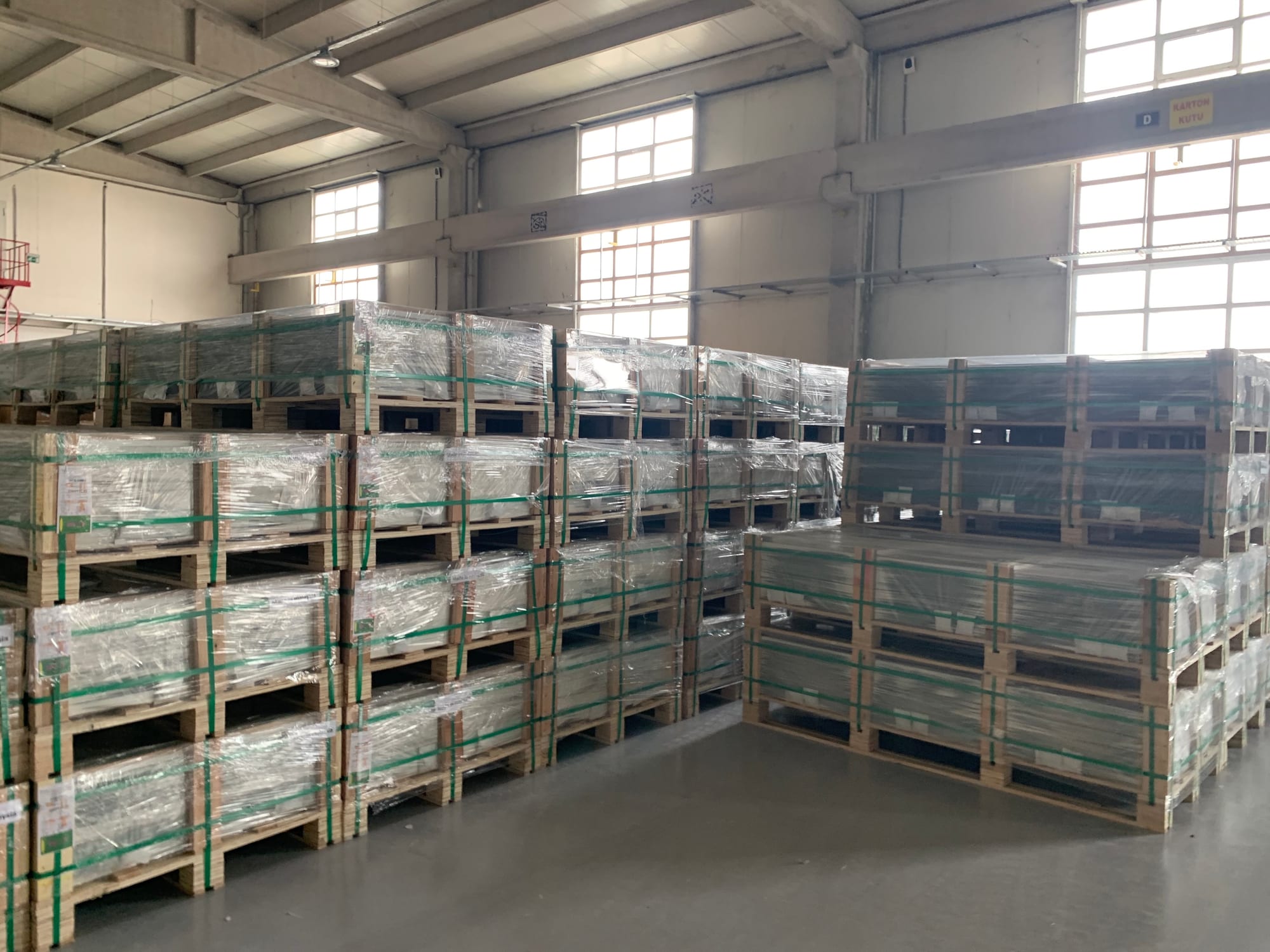 Üretim denetimi sırasında fabrika depolama alanında paletlenmiş güneş panelleri